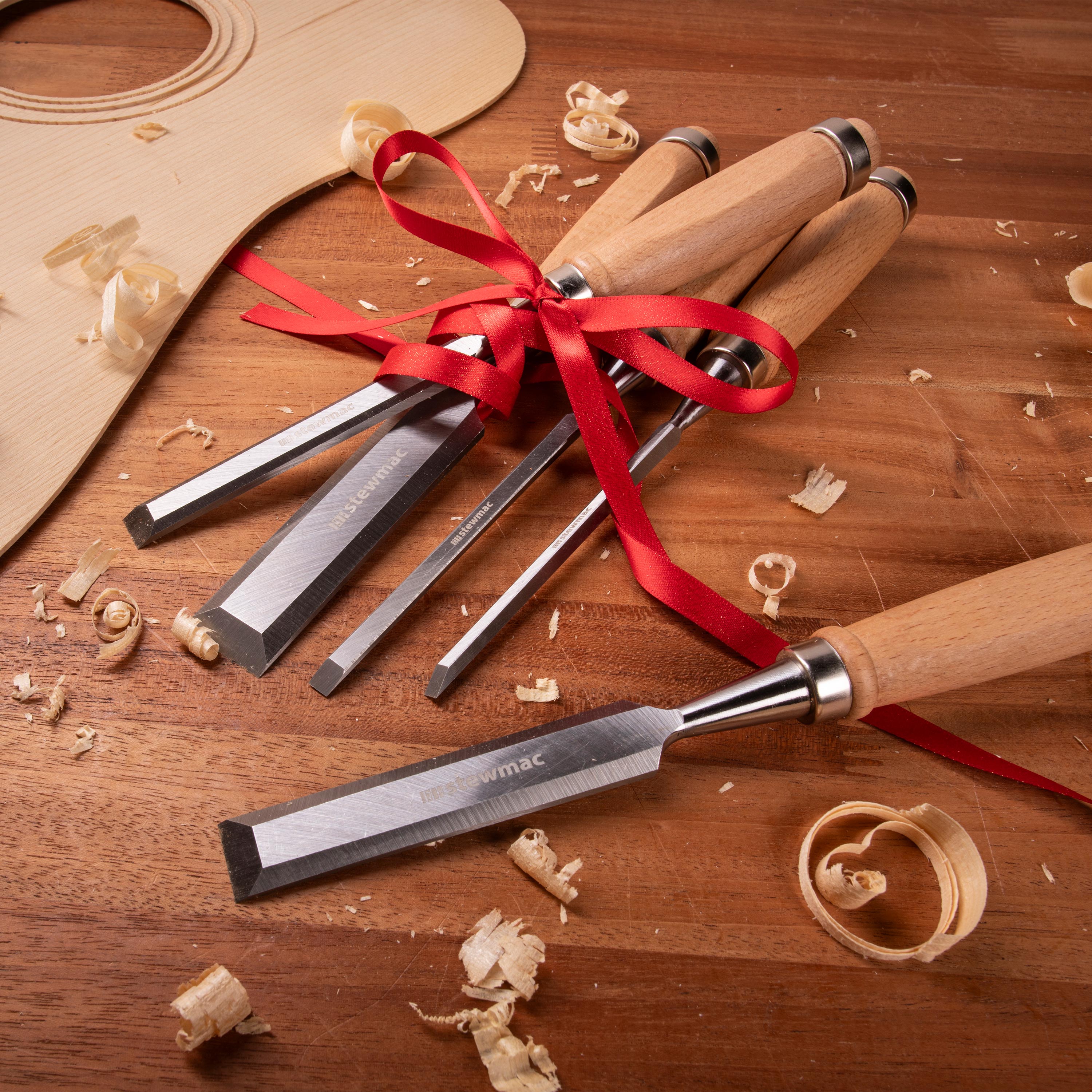 Jeu de burins en bois sur un banc de travail avec ruban cadeau.