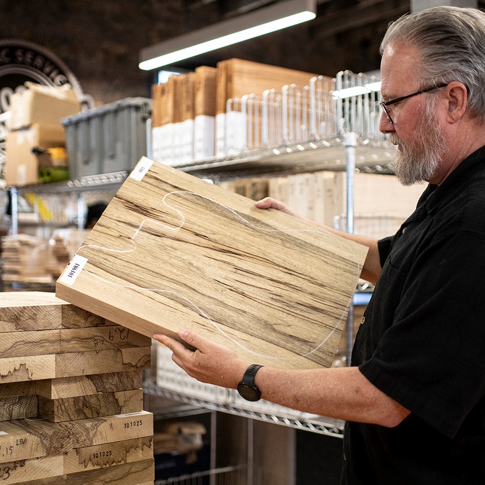 Chris inspectant notre sélection WoodStax de cales de corps Black Limba pour la fabrication de guitares.