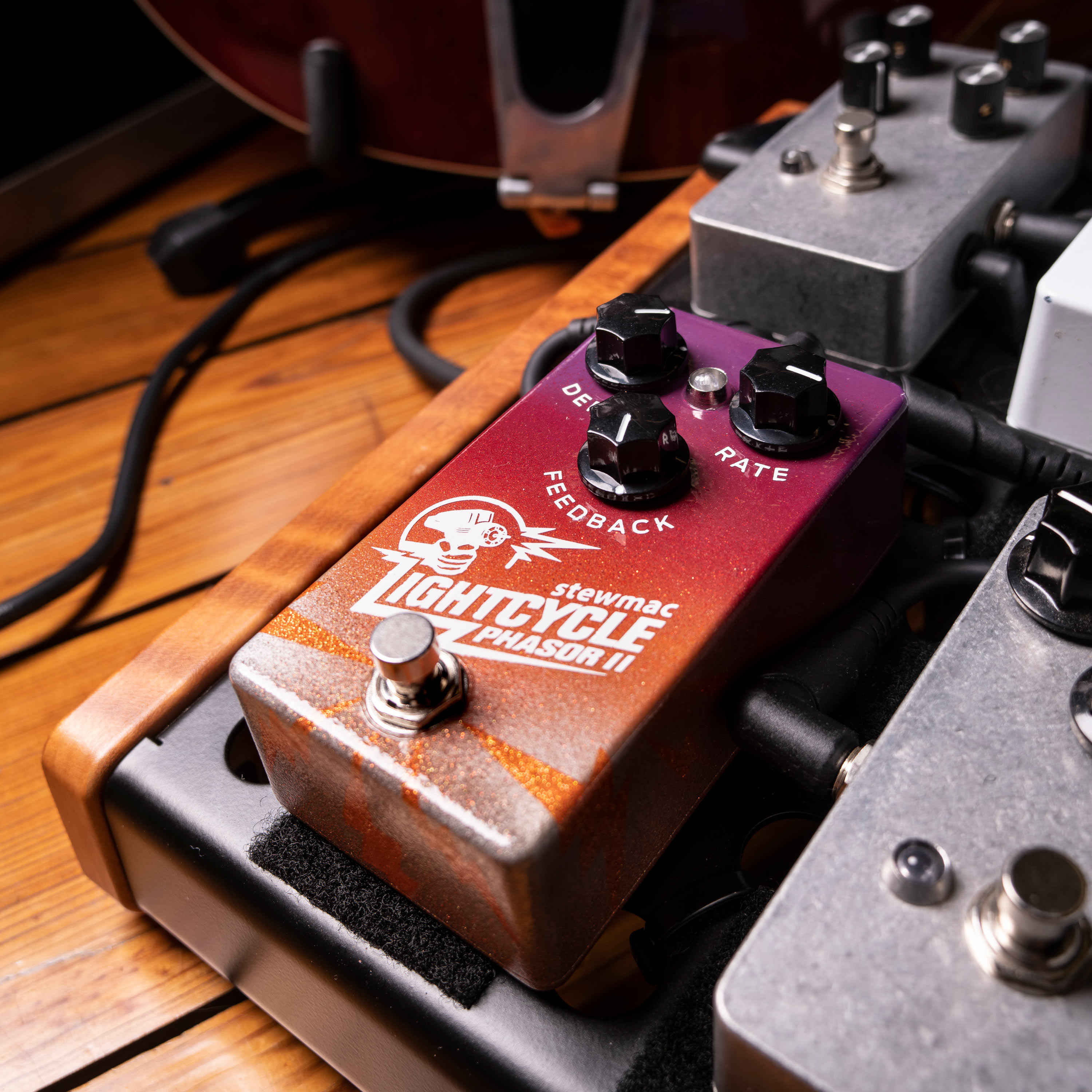 Pédale Lightcycle Phasor II sur le panneau de pédales avec câbles de guitare au sol.