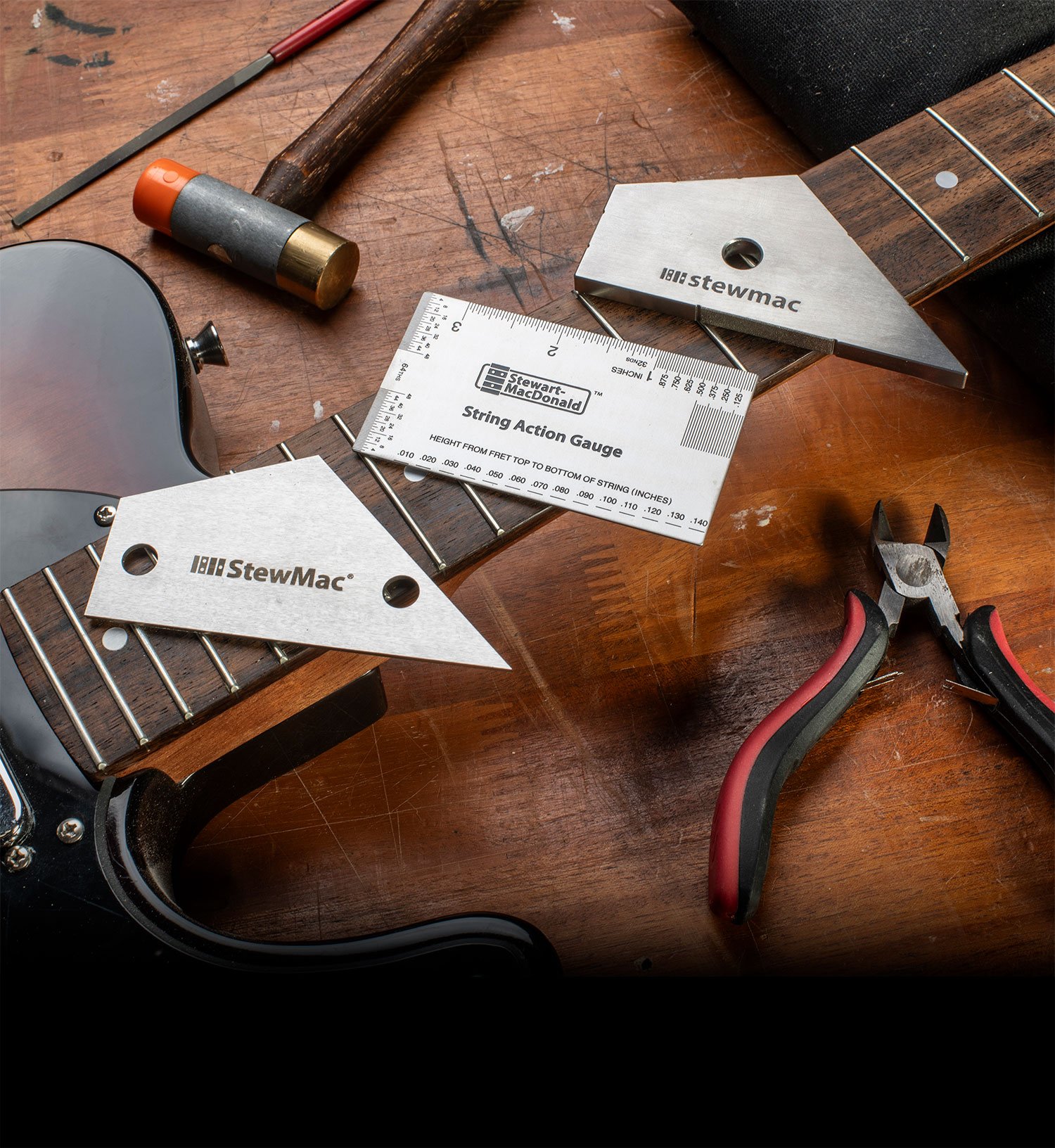 Outils de travail à frett essentiels reposant sur une manche de guitare sur un établi.