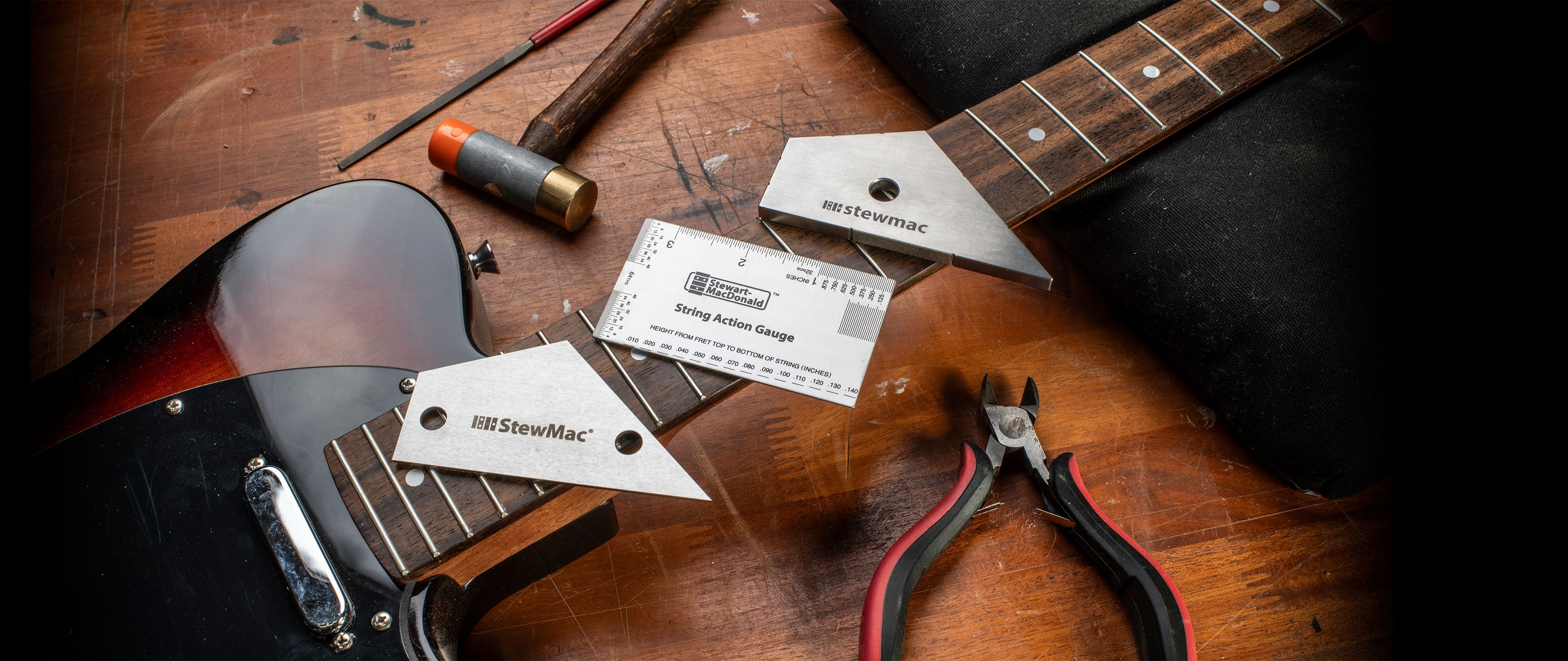 Outils de travail à frett essentiels reposant sur une manche de guitare sur un établi.
