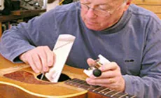 Dan Atteignant l’intérieur d’une guitare