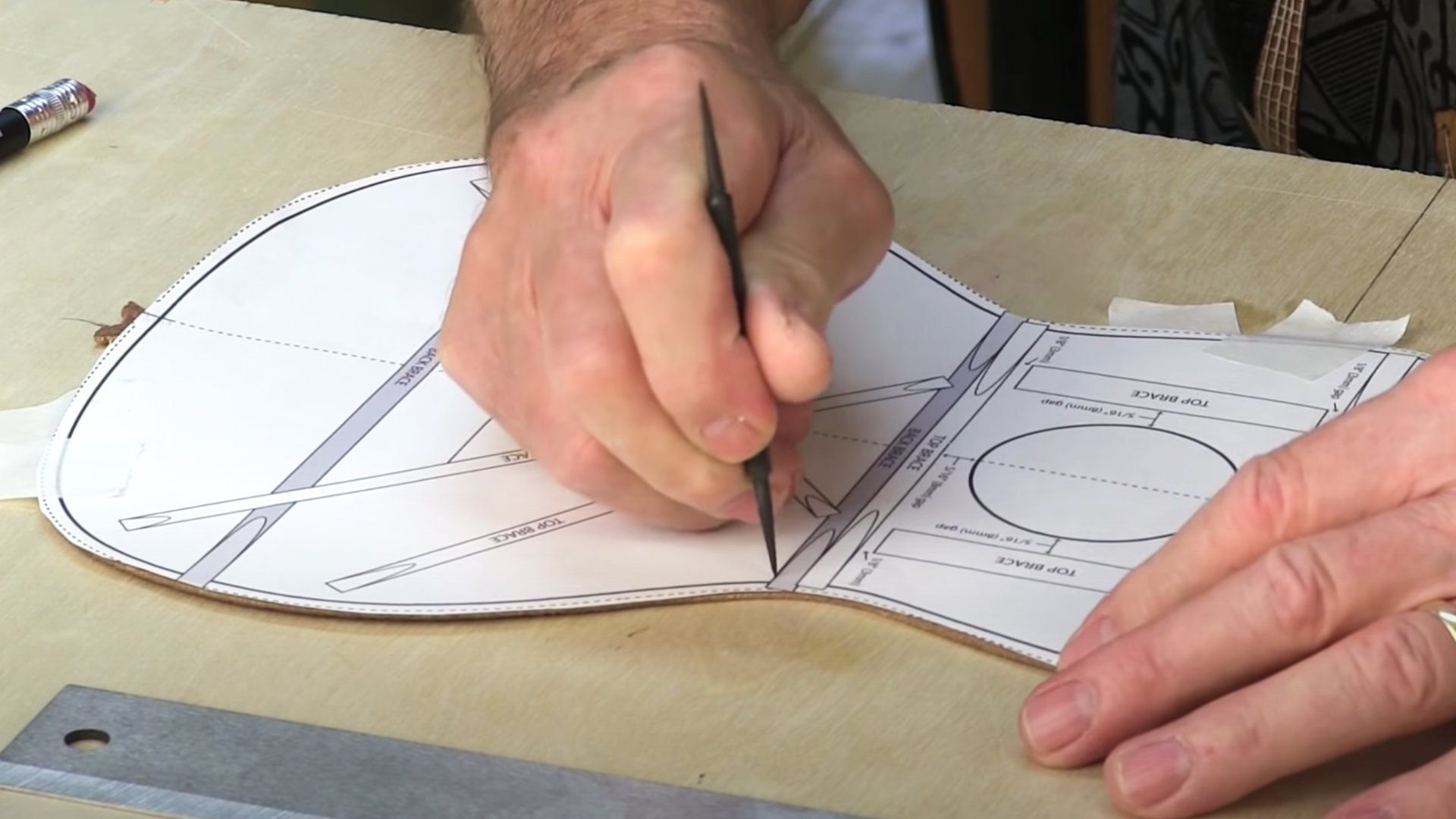 Mains traçant le motif ukulele avec scribe