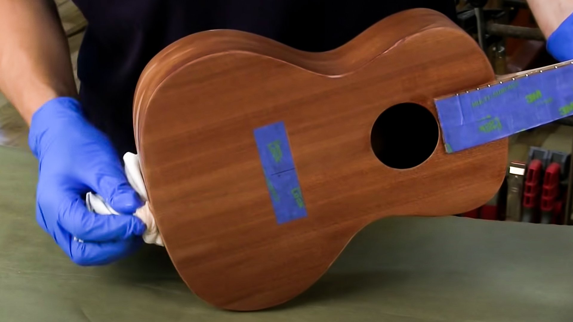 Mains essuyant le manteau de finition sur le corps des ukules avec un chiffon