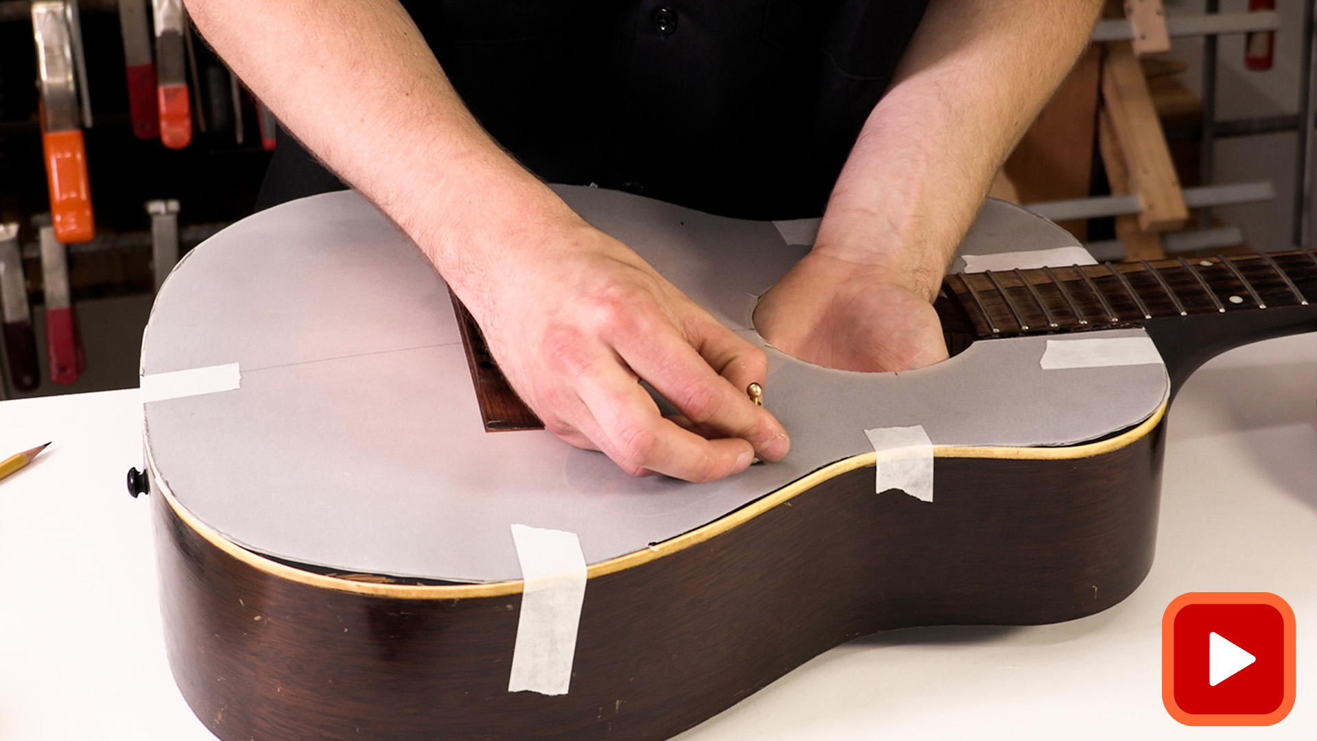 Mains attachant le papier calque au haut de la guitare acoustique